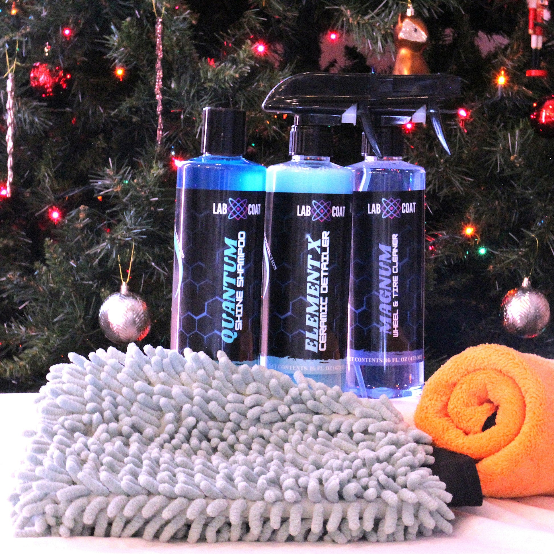 Cleaning products and microfiber cloths in front of a decorated Christmas tree